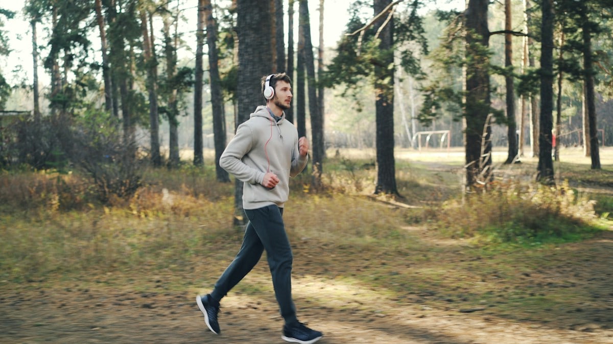 Man running in a forest with headphones on