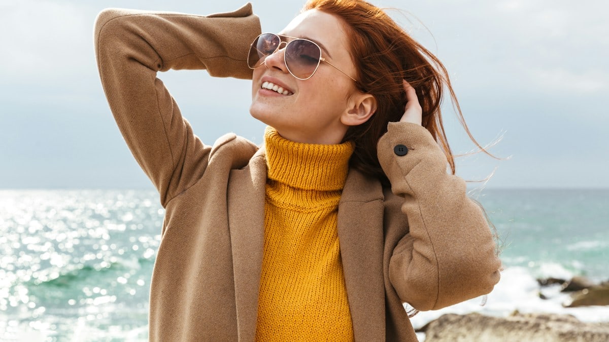 a woman with red hair and sunglasses on a beach